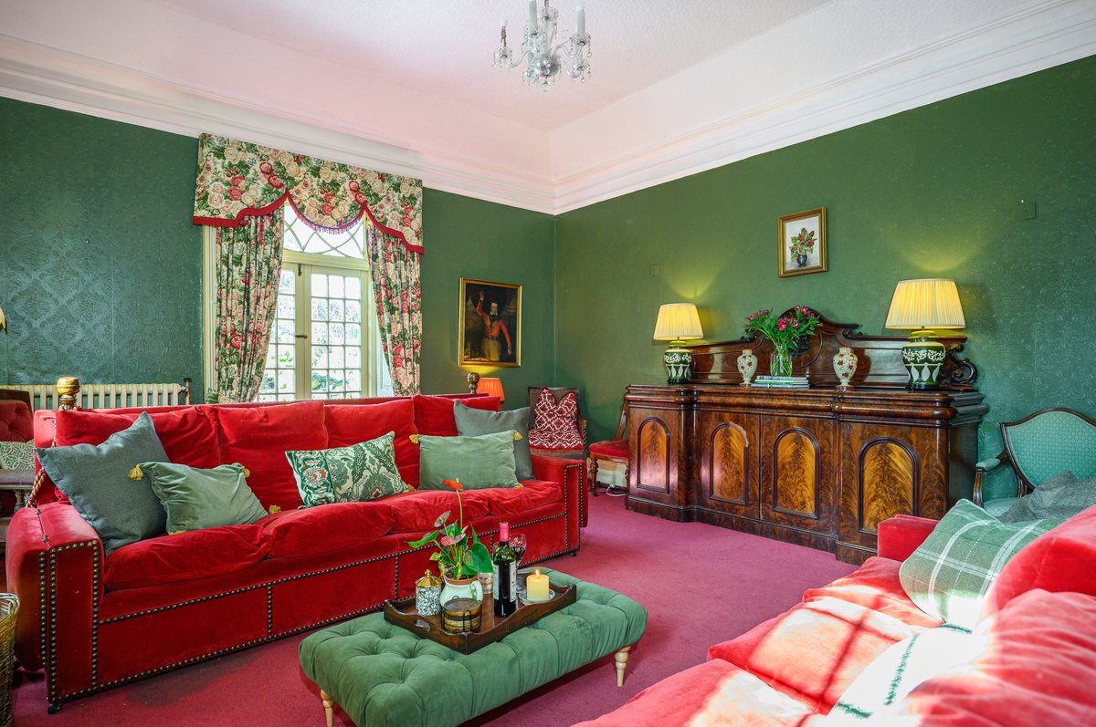 Spacious lounge in group accommodation with open fire and velvet sofas