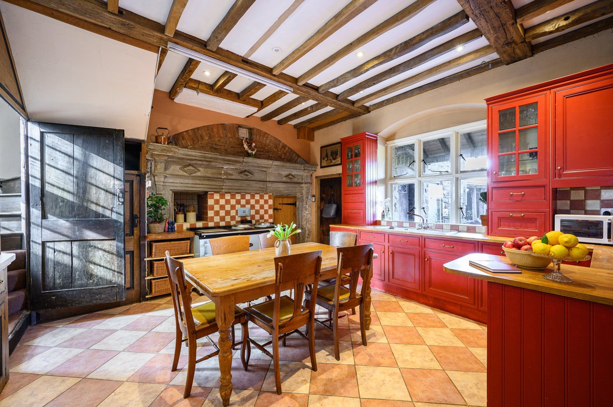 Large farmhouse kitchen in Gloucestershire manor with Aga and stone fireplace
